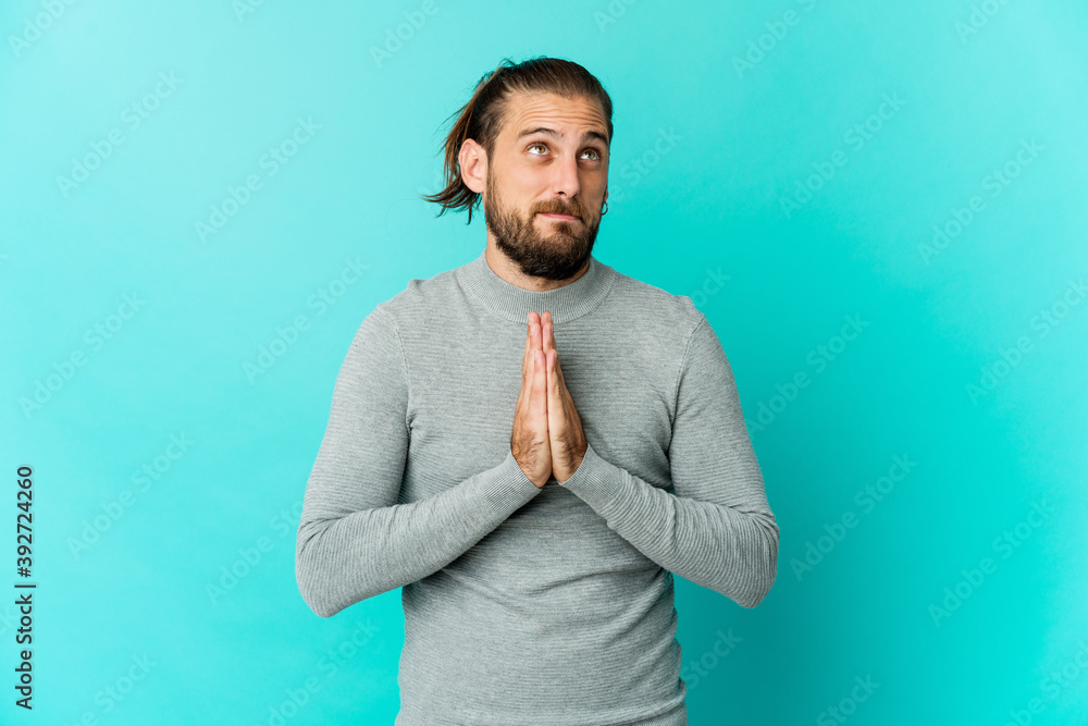 Young man with long hair look praying, showing devotion, religious person looking for divine inspiration. Young man with long hair look praying, showing devotion, religious person looking for divine inspiration.