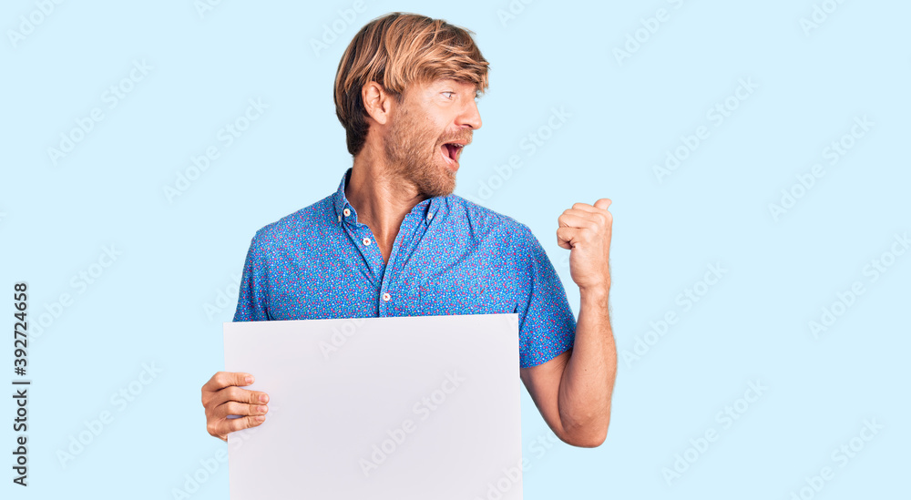 Handsome caucasian man with beard holding sale poster pointing thumb up to the side smiling happy with open mouth Handsome caucasian man with beard holding sale poster pointing thumb up to the side smiling happy with open mouth