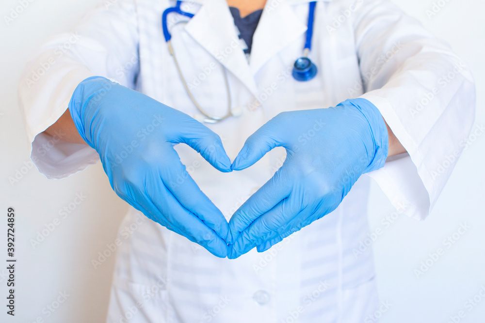 The doctor hands show folded hands into a heart. Medical gloves on hands to protect against infection. Invention of vaccines to treat viruses, diseases, bacteria, influenza. Concept care with love. The doctor hands show folded hands into a heart. Medical gloves on hands to protect against infection. Invention of vaccines to treat viruses, diseases, bacteria, influenza. Concept care with love.