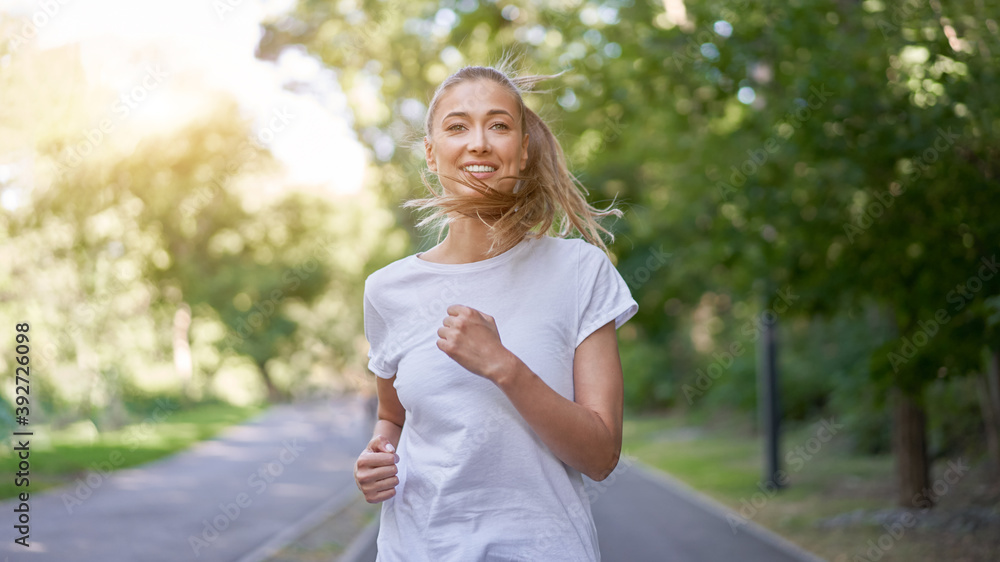 Woman running asphalt road summer park