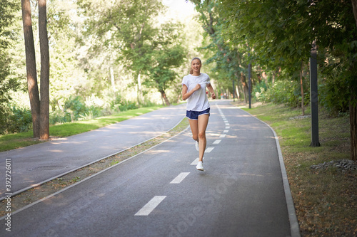 Woman running asphalt road summer park