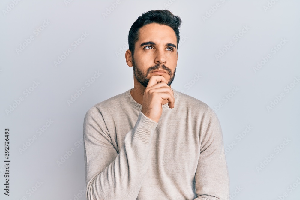 Young hispanic man wearing casual clothes thinking concentrated about doubt with finger on chin and looking up wondering Young hispanic man wearing casual clothes thinking concentrated about doubt with finger on chin and looking up wondering