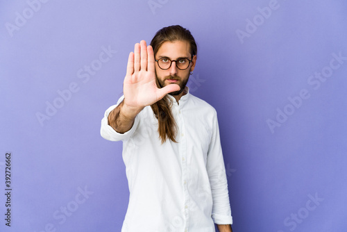 Young man with long hair look standing with outstretched hand showing stop sign, preventing you.