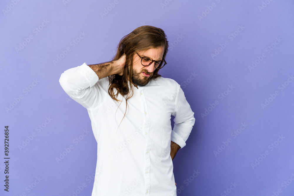 Young man with long hair look having a neck pain due to stress, massaging and touching it with hand. Young man with long hair look having a neck pain due to stress, massaging and touching it with hand.