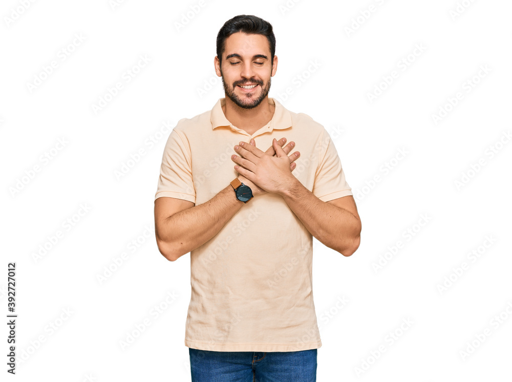 Young hispanic man wearing casual clothes smiling with hands on chest with closed eyes and grateful gesture on face. health concept. Young hispanic man wearing casual clothes smiling with hands on chest with closed eyes and grateful gesture on face. health concept.