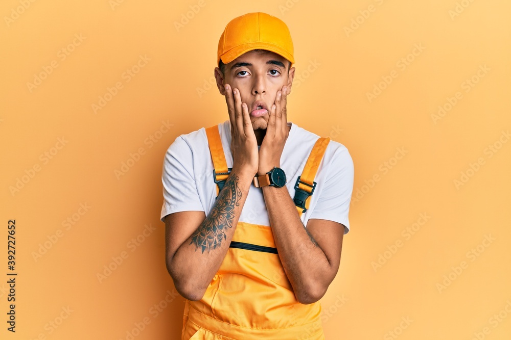 Young handsome african american man wearing handyman uniform over yellow background tired hands covering face, depression and sadness, upset and irritated for problem