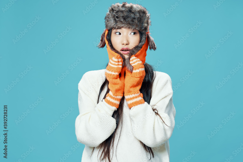 Asian woman in warm caps on a blue background
