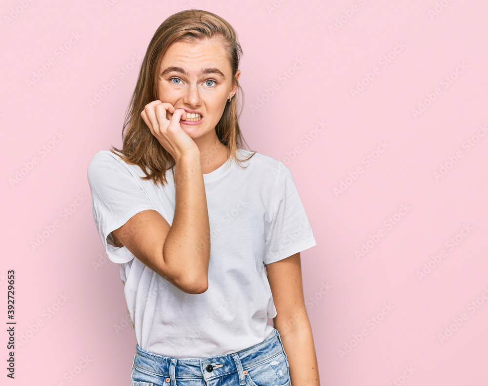 Beautiful young blonde woman wearing casual white t shirt looking stressed and nervous with hands on mouth biting nails. anxiety problem. Beautiful young blonde woman wearing casual white t shirt looking stressed and nervous with hands on mouth biting nails. anxiety problem.