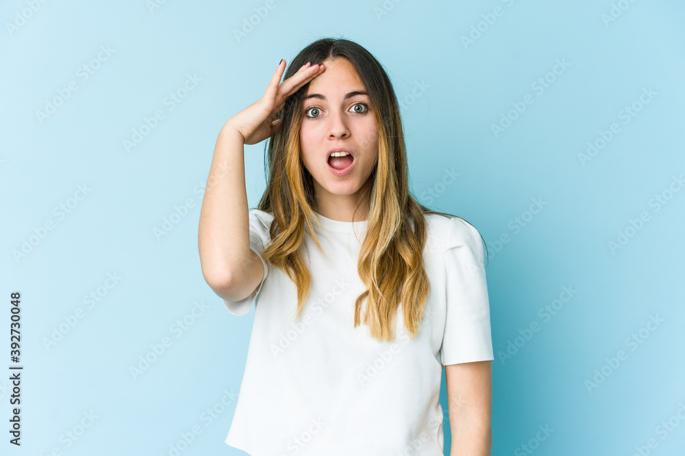 Young caucasian woman isolated on blue background shouts loud, keeps eyes opened and hands tense. Young caucasian woman isolated on blue background shouts loud, keeps eyes opened and hands tense.