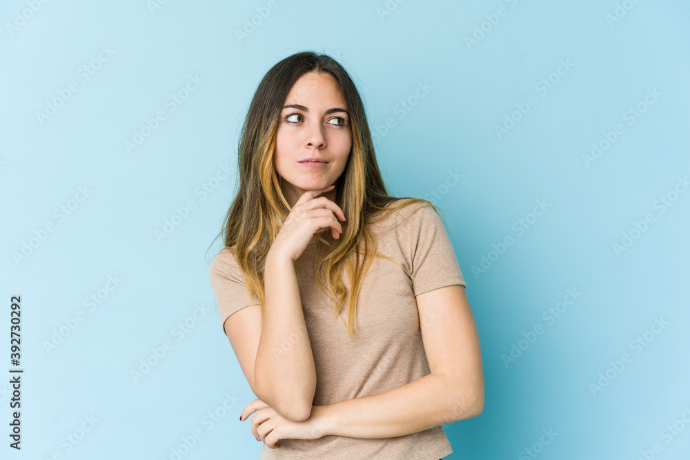 Young caucasian woman isolated on blue background looking sideways with doubtful and skeptical expression. Young caucasian woman isolated on blue background looking sideways with doubtful and skeptical expression.