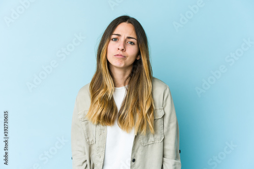 Young caucasian woman isolated on blue background sad, serious face, feeling miserable and displeased.
