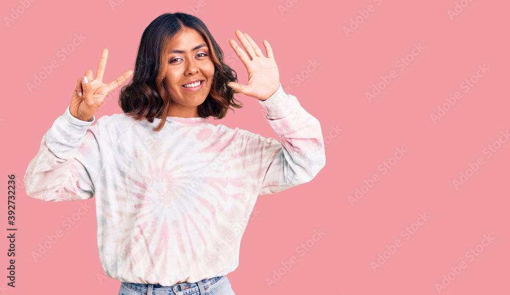 Young beautiful mixed race woman wearing casual tie dye sweatshirt showing and pointing up with fingers number seven while smiling confident and happy. Young beautiful mixed race woman wearing casual tie dye sweatshirt showing and pointing up with fingers number seven while smiling confident and happy.