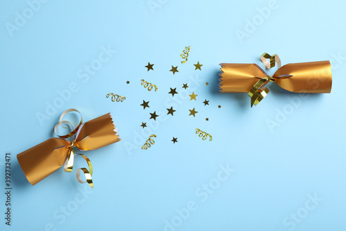 Billede på lærred Open golden Christmas cracker with shiny confetti on light blue background, top