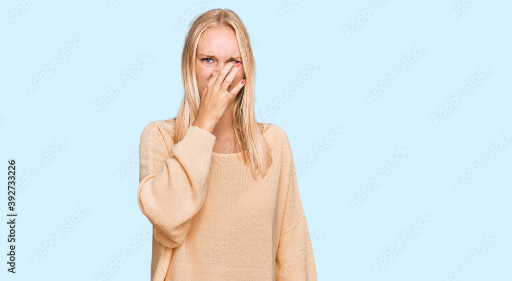 Young blonde girl wearing casual clothes smelling something stinky and disgusting, intolerable smell, holding breath with fingers on nose. bad smell Young blonde girl wearing casual clothes smelling something stinky and disgusting, intolerable smell, holding breath with fingers on nose. bad smell