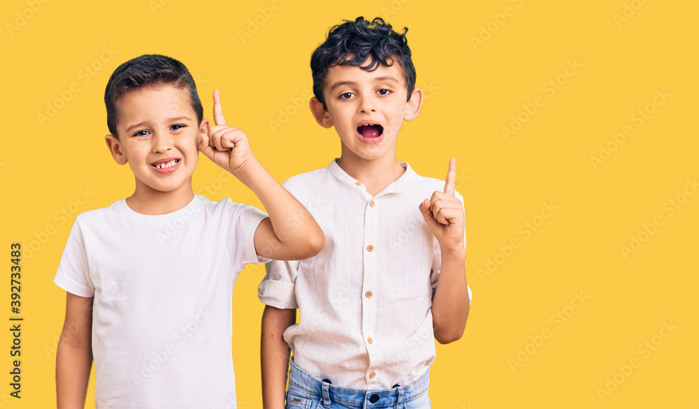 Couple of little brothers together wearing casual clothes pointing finger up with successful idea. exited and happy. number one. Couple of little brothers together wearing casual clothes pointing finger up with successful idea. exited and happy. number one.