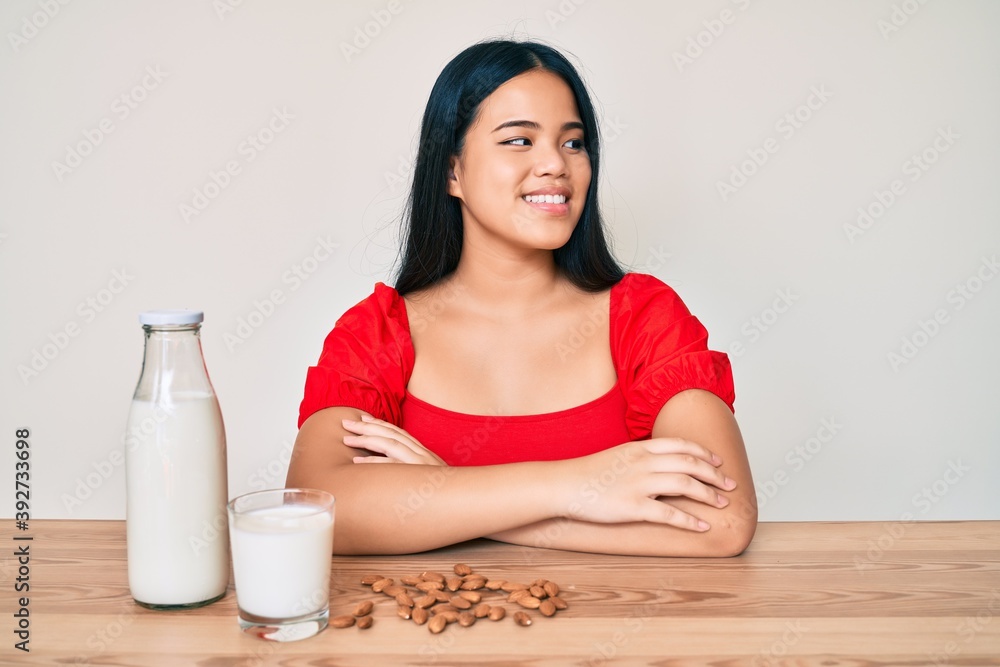 Young asian girl drinking healthy almond milk looking to side, relax profile pose with natural face and confident smile. Young asian girl drinking healthy almond milk looking to side, relax profile pose with natural face and confident smile.