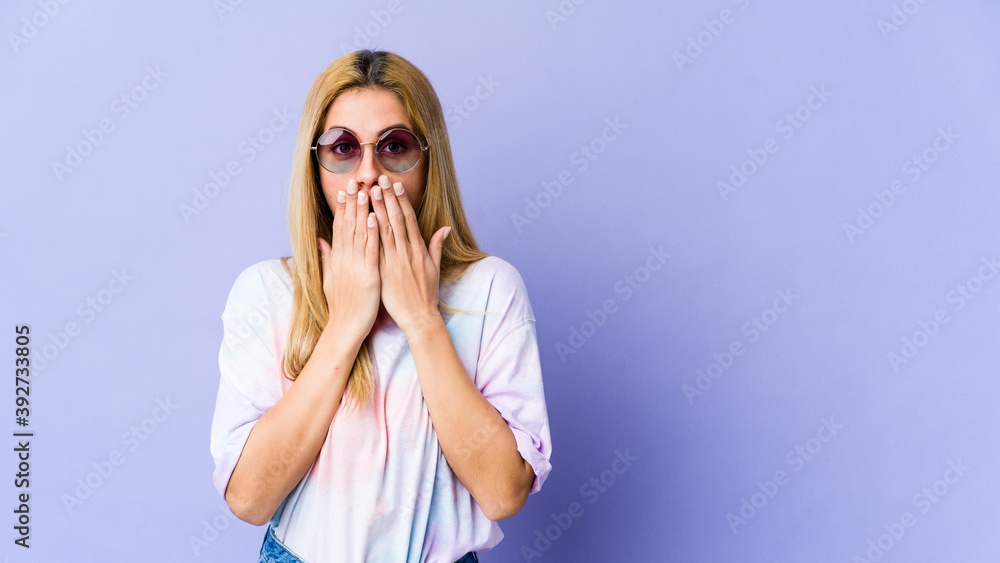 Young blonde caucasian woman shocked, covering mouth with hands, anxious to discover something new.