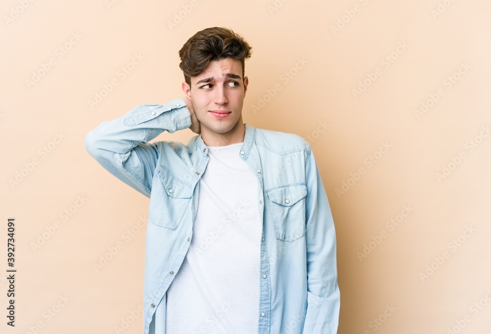 Young caucasian man isolated on beige background touching back of head, thinking and making a choice. Young caucasian man isolated on beige background touching back of head, thinking and making a choice.