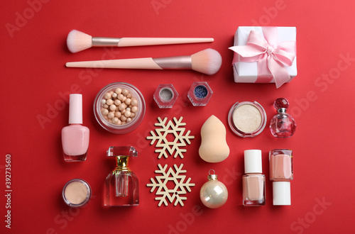 Flat lay composition with decorative cosmetic products on red background. Winter care
