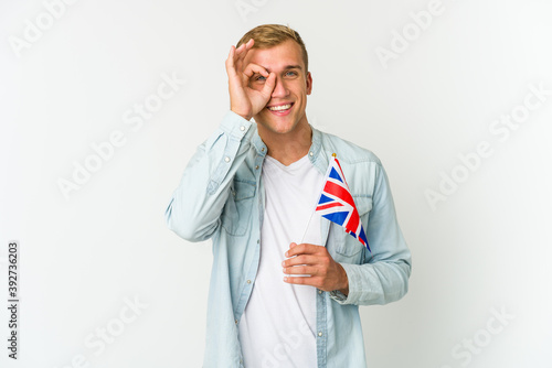 Young caucasian man holding a united kingdom flag isolated on white background