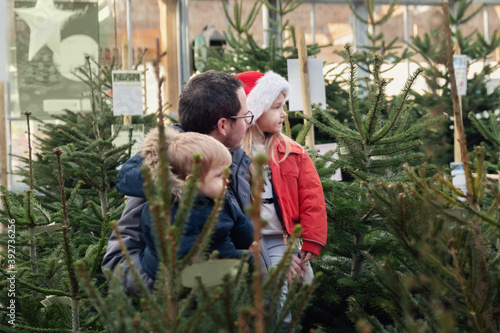 Father and kids choose a Christmas tree in a shop