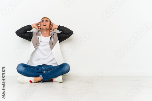 Young caucasian man sitting on the floor screaming with rage.