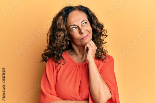 Middle age hispanic woman wearing casual clothes serious face thinking about question with hand on chin, thoughtful about confusing idea