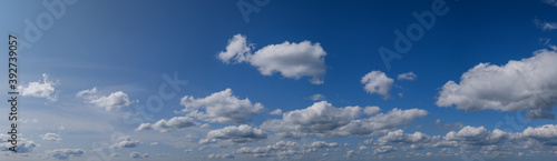 Blue sky with clouds in sunshine (wide natural cloudscape background panorama)