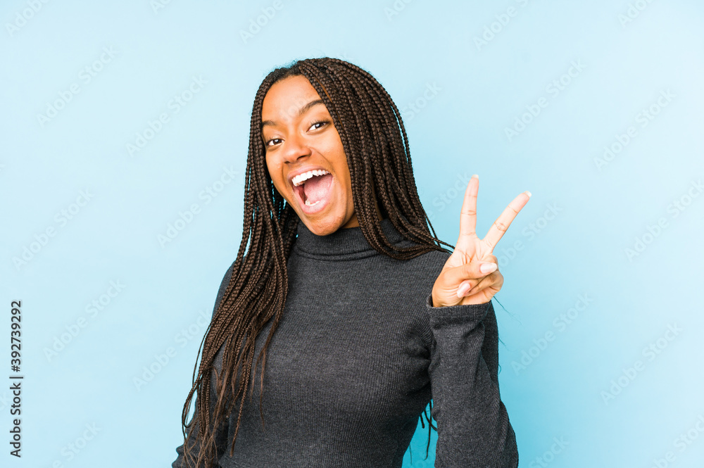 Φωτογραφία Young african american woman isolated on blue background joyful and carefree showing a peace symbol with fingers