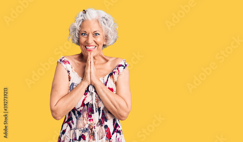 Senior grey-haired woman wearing casual clothes praying with hands together asking for forgiveness smiling confident.