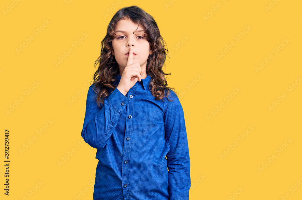 Cute child with long hair wearing casual clothes asking to be quiet with finger on lips. silence and secret concept. Cute child with long hair wearing casual clothes asking to be quiet with finger on lips. silence and secret concept.