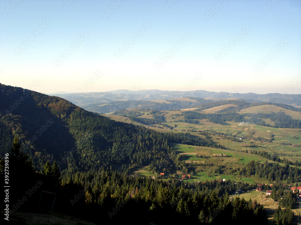View of the Carpathian Mountains from Mount Gimba. Forests and houses in the valleys against the sky