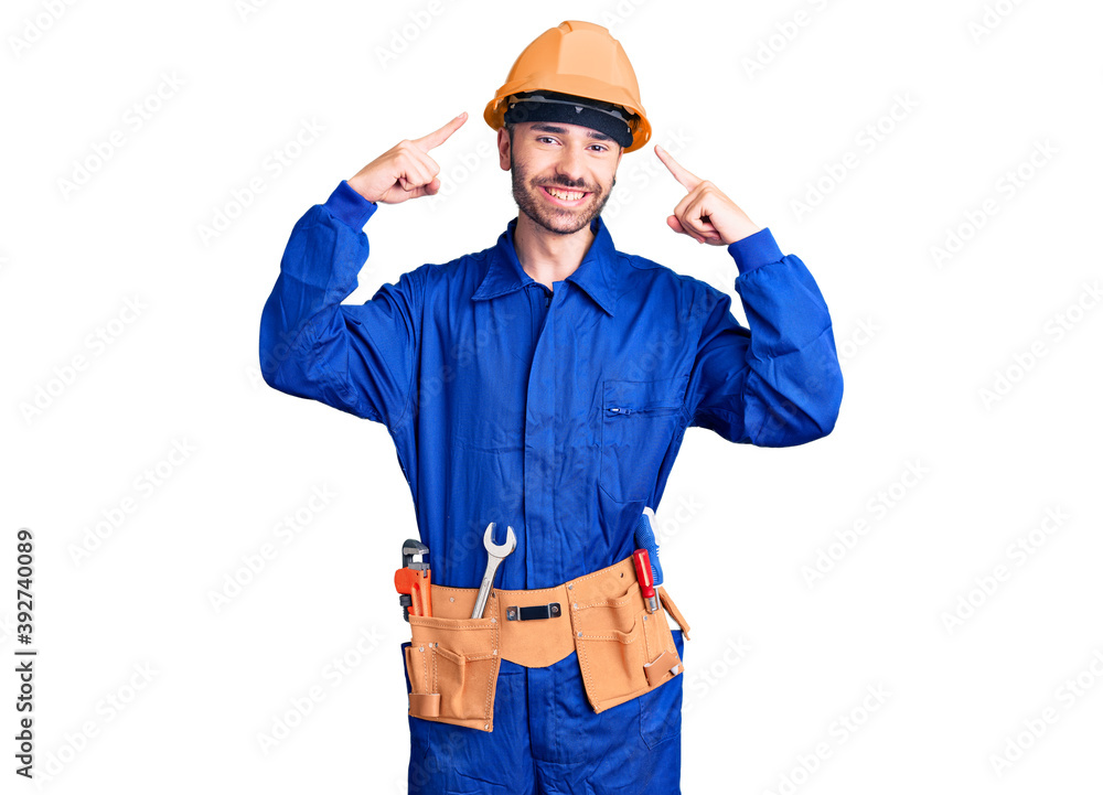 Young hispanic man wearing worker uniform smiling pointing to head with both hands finger, great idea or thought, good memory Young hispanic man wearing worker uniform smiling pointing to head with both hands finger, great idea or thought, good memory
