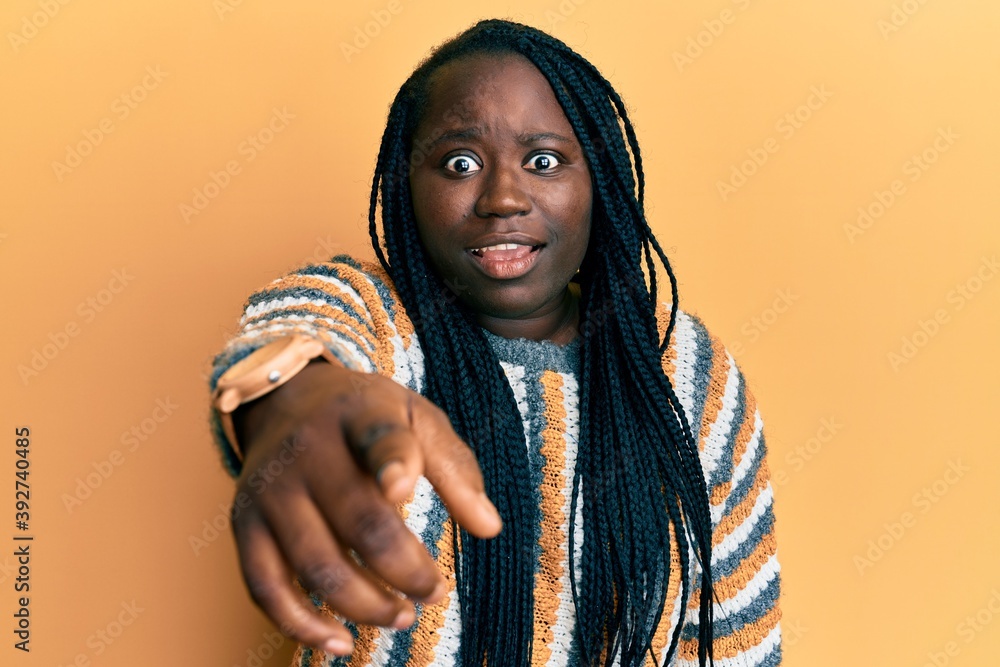 Young black woman with braids wearing casual winter sweater pointing displeased and frustrated to the camera, angry and furious with you Young black woman with braids wearing casual winter sweater pointing displeased and frustrated to the camera, angry and furious with you