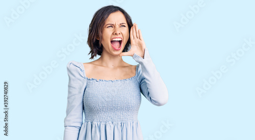 Young beautiful girl wearing casual clothes shouting and screaming loud to side with hand on mouth. communication concept.