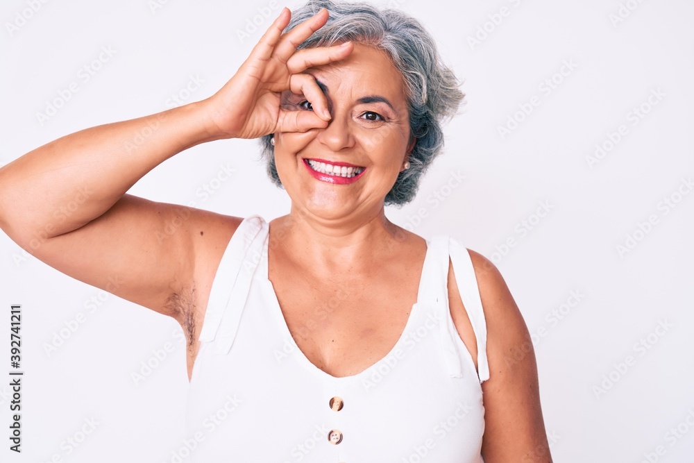 Senior hispanic woman wearing casual clothes smiling happy doing ok sign with hand on eye looking through fingers Senior hispanic woman wearing casual clothes smiling happy doing ok sign with hand on eye looking through fingers
