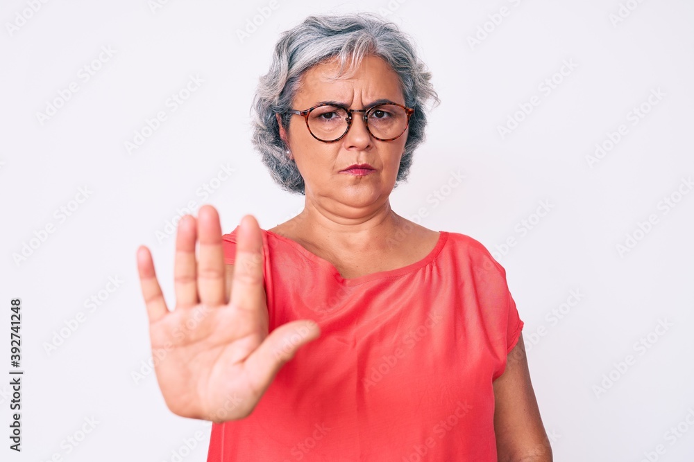 Senior hispanic grey- haired woman wearing casual clothes and glasses doing stop sing with palm of the hand. warning expression with negative and serious gesture on the face. Senior hispanic grey- haired woman wearing casual clothes and glasses doing stop sing with palm of the hand. warning expression with negative and serious gesture on the face.