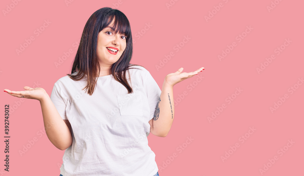 Young plus size woman wearing casual clothes smiling showing both hands open palms, presenting and advertising comparison and balance Young plus size woman wearing casual clothes smiling showing both hands open palms, presenting and advertising comparison and balance