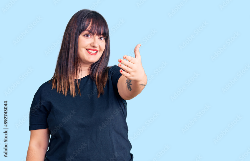 Young plus size woman wearing casual clothes smiling friendly offering handshake as greeting and welcoming. successful business. Young plus size woman wearing casual clothes smiling friendly offering handshake as greeting and welcoming. successful business.