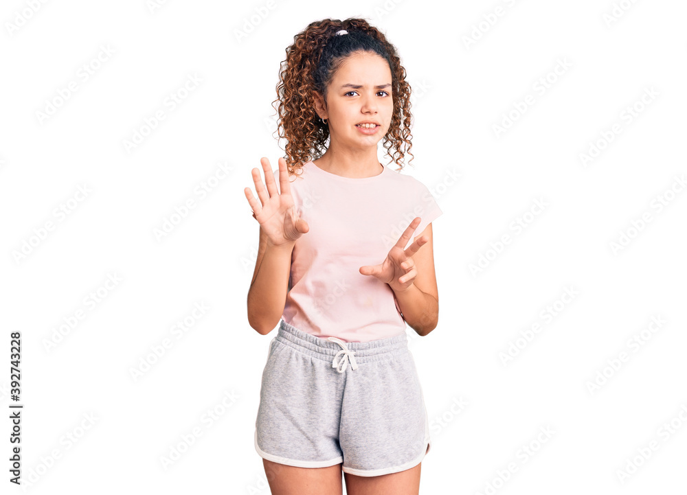 Beautiful kid girl with curly hair wearing casual clothes disgusted expression, displeased and fearful doing disgust face because aversion reaction. with hands raised Beautiful kid girl with curly hair wearing casual clothes disgusted expression, displeased and fearful doing disgust face because aversion reaction. with hands raised