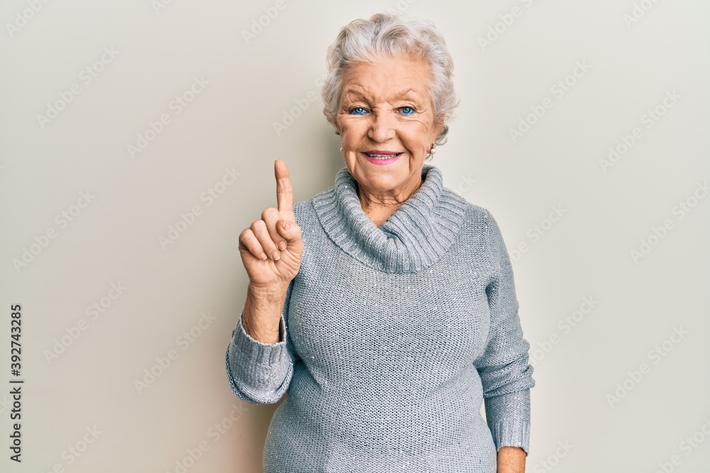 Senior grey-haired woman wearing casual clothes smiling with an idea or question pointing finger up with happy face, number one Senior grey-haired woman wearing casual clothes smiling with an idea or question pointing finger up with happy face, number one