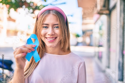 Wallpaper Mural Young caucasian girl smiling happy holding blue cancer ribbon at the city. Torontodigital.ca