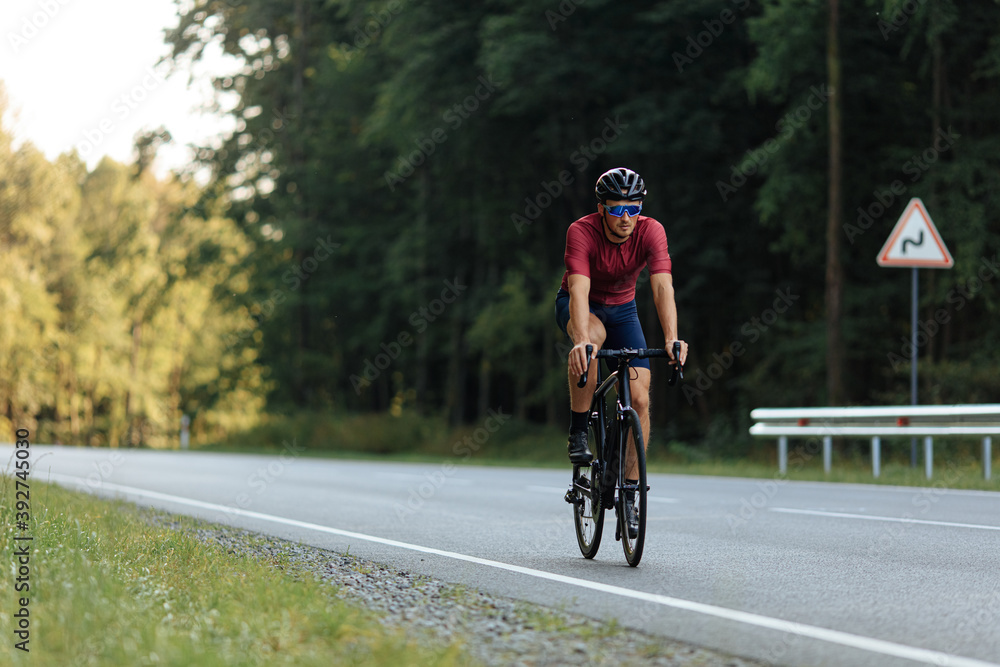 Young athlete in helmet riding bike on paved road Young athlete in helmet riding bike on paved road