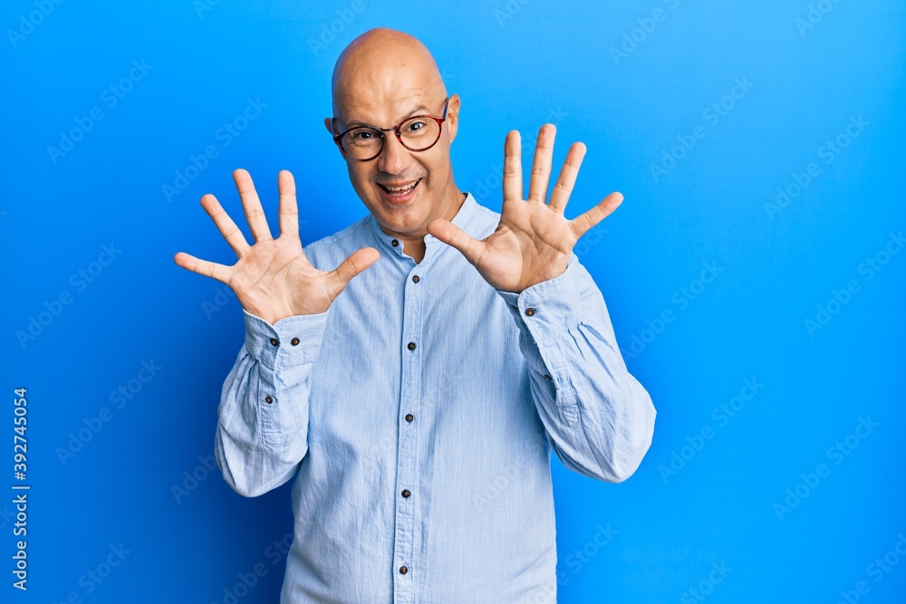 Middle age bald man wearing casual clothes and glasses showing and pointing up with fingers number ten while smiling confident and happy.