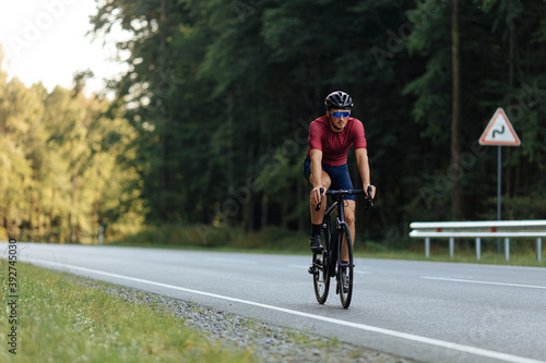 Young athlete in helmet riding bike on paved road