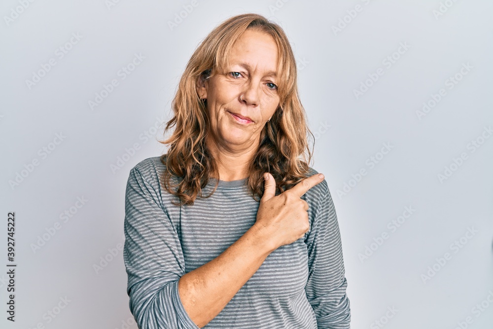 Middle age blonde woman wearing casual clothes smiling cheerful pointing with hand and finger up to the side Middle age blonde woman wearing casual clothes smiling cheerful pointing with hand and finger up to the side