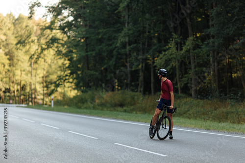 Fototapeta Naklejka Na Ścianę i Meble -  Professional cyclist standing on paved road with bike