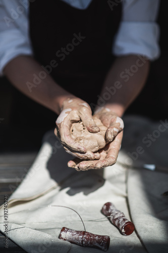 Close up of woman hands works with clay. Female potter kneads and moistens the clay before work.