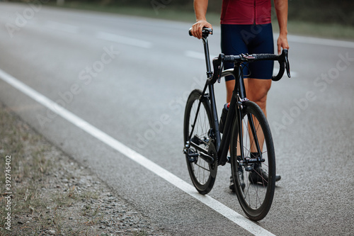 Male cyclist standing on road with black bike