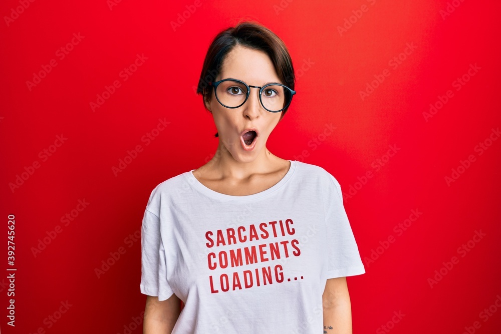 Fototapeta premium Young brunette woman with short hair wearing sarcastic comments loading t-shirt scared and amazed with open mouth for surprise, disbelief face